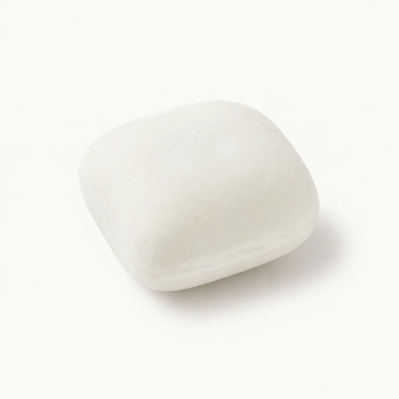 Photo-informed illustration of a white, rounded-square Buzzin gum piece with a gently domed top